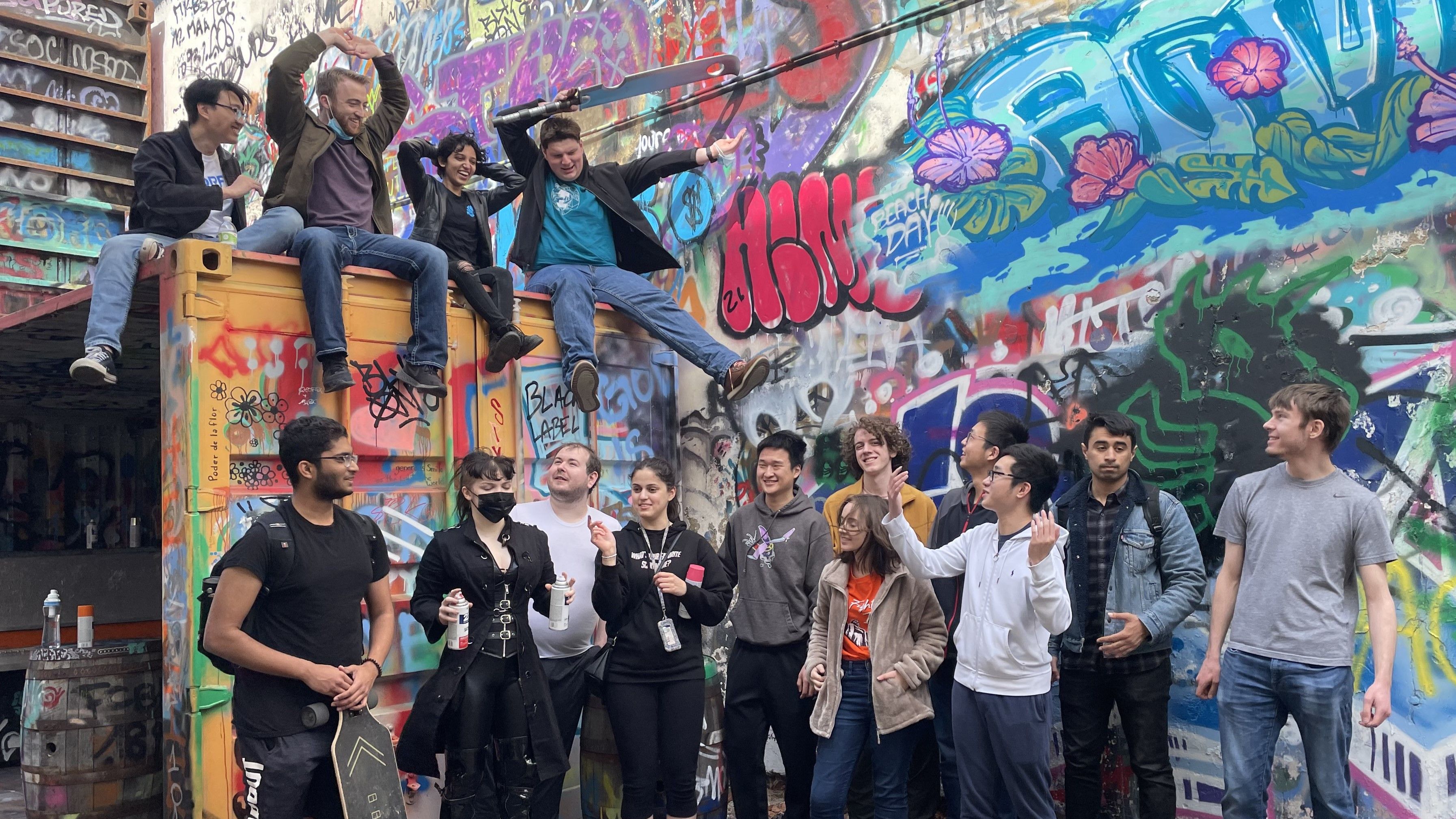 SIGPwny members laughing in front of grafitti during a spray paint social event